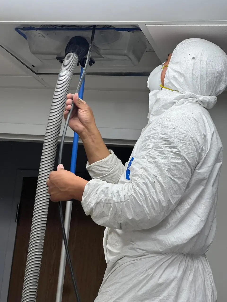 Technician running an agitation whip into a ceiling supply vent