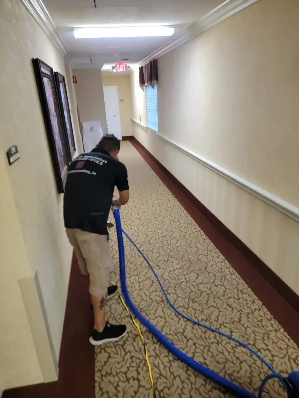 Technician cleaning a long commercial hallway carpet