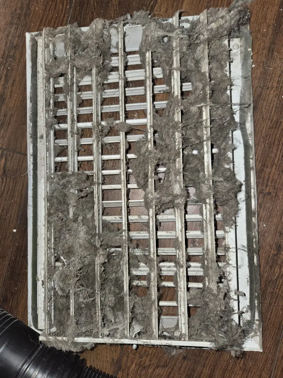 Return air grille covered in thick dust before cleaning