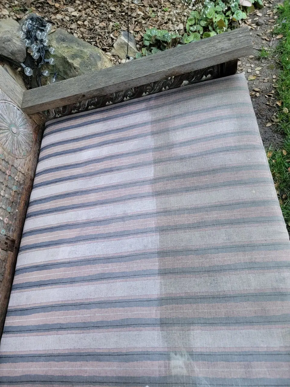 Striped outdoor bench cushion, half cleaned