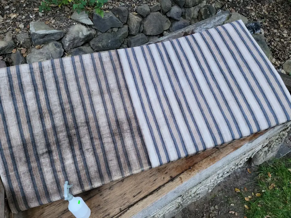 Outdoor cushion on a wooden bench, the clean half next to the soiled half