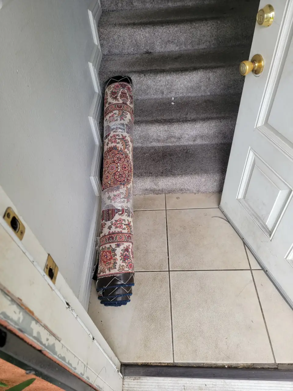 Rolled rug at a front door, ready for pickup