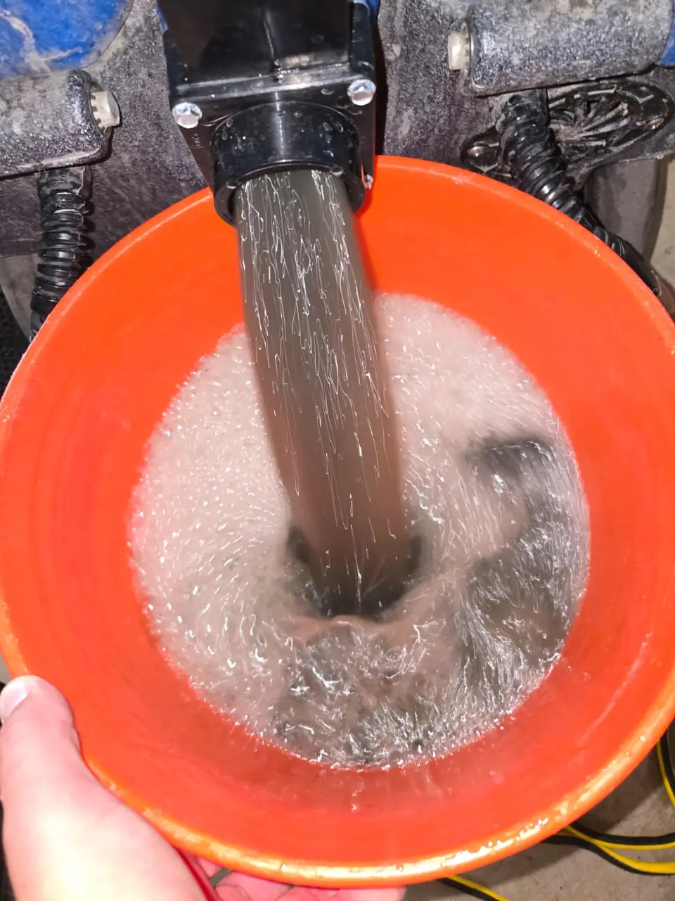 Dirty rinse water from a rug wash pouring into a bucket
