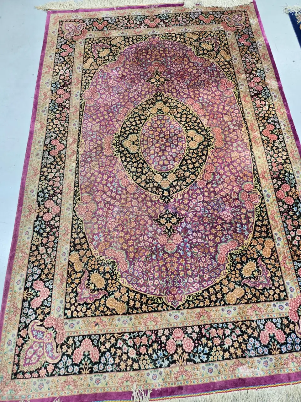 Silk rug with a pink and purple floral field, laid flat after cleaning