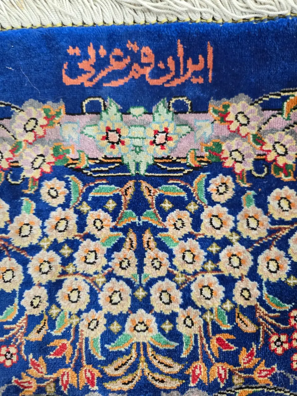 Close-up of a silk rug with a signature cartouche