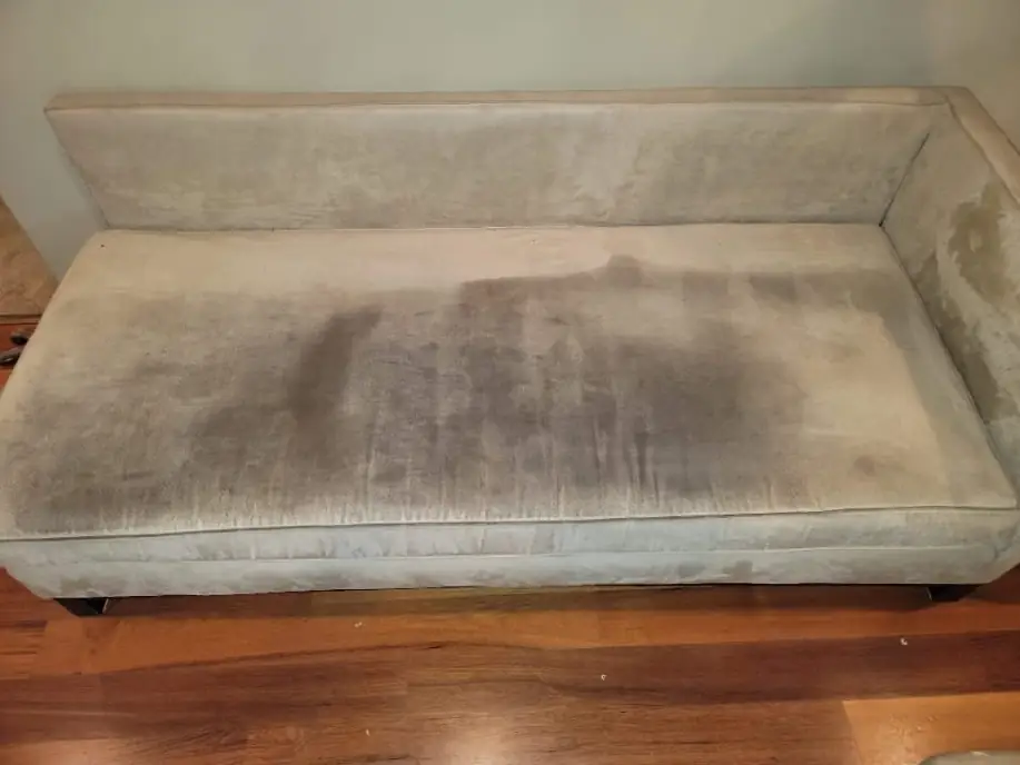 Light fabric sofa seat with dark soiling before cleaning